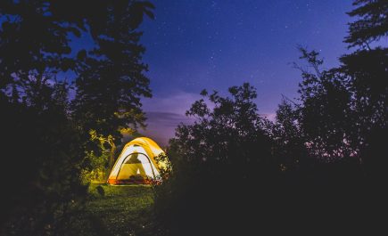 A tent lit from inside, glowing against a dark sky.